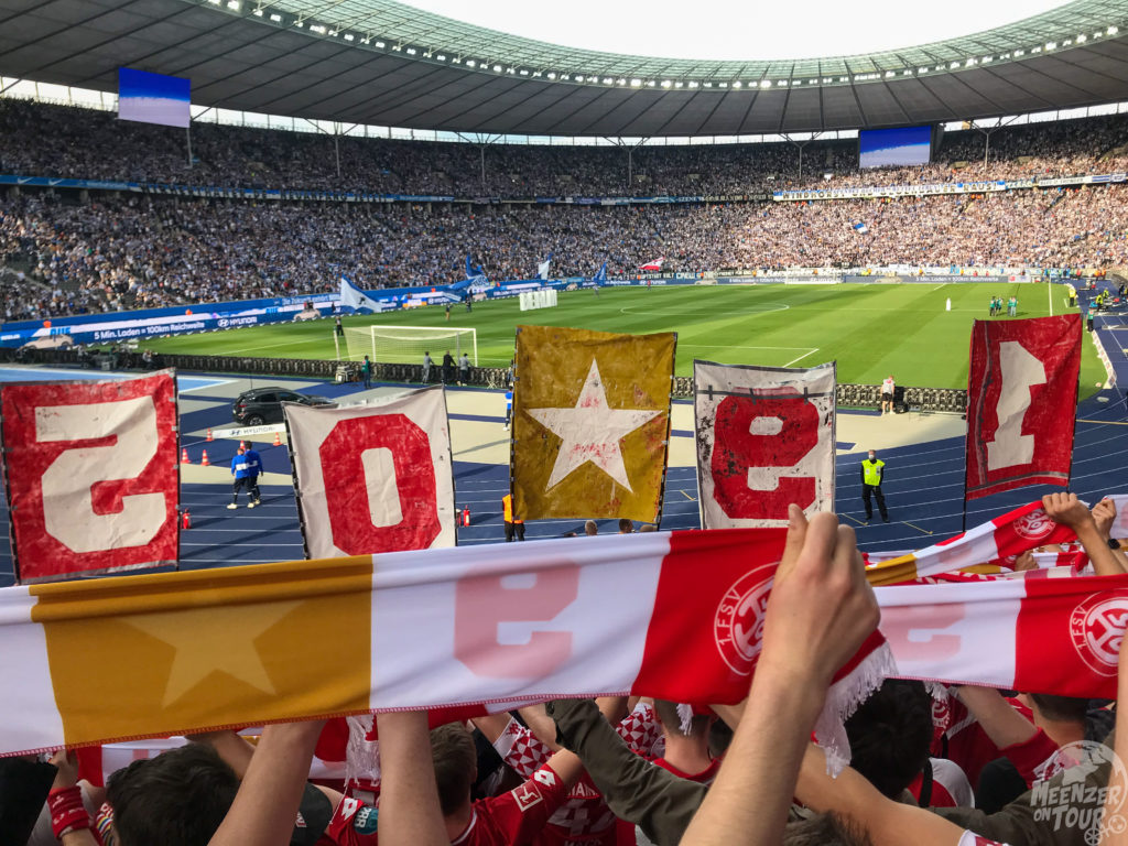 Mainzer Fans halten den Spieltagsschal im Gästeblock des Olympiastadions hoch